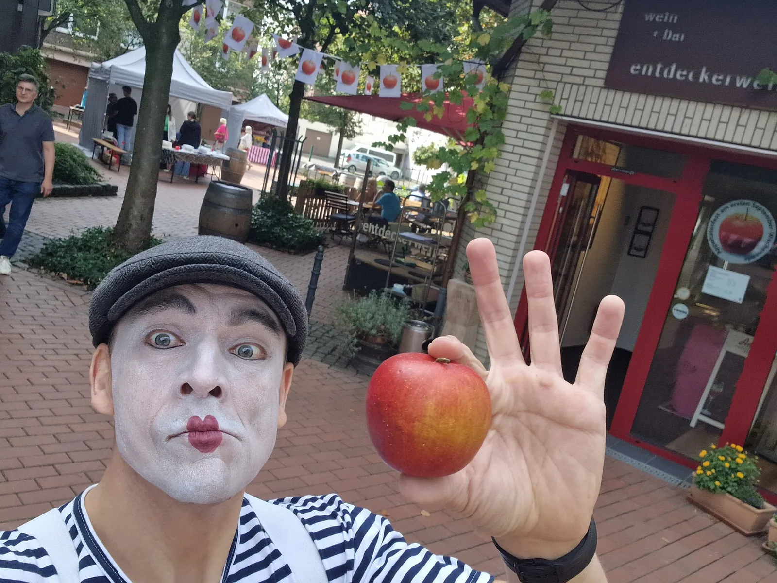 Pantomime LIAR mit rotem Apfel begrüßt einen Gast beim Stadtfest